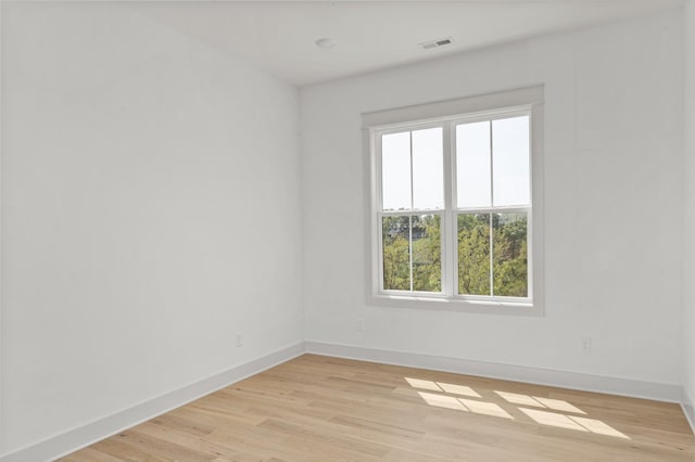 spare room featuring light wood-style flooring, visible vents, and baseboards