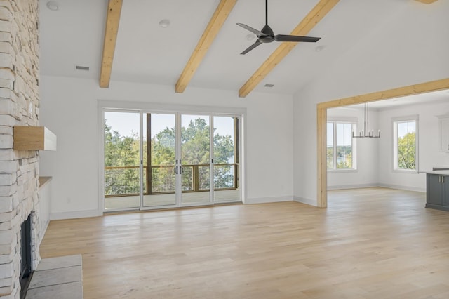 unfurnished living room with ceiling fan with notable chandelier, beamed ceiling, a fireplace, and light wood-style flooring