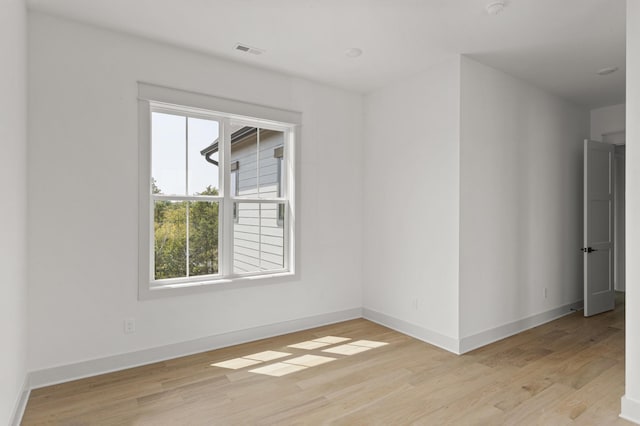 spare room featuring baseboards, visible vents, and light wood finished floors