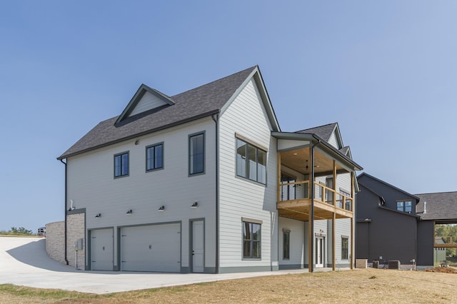 rear view of property with a balcony, a shingled roof, and a garage