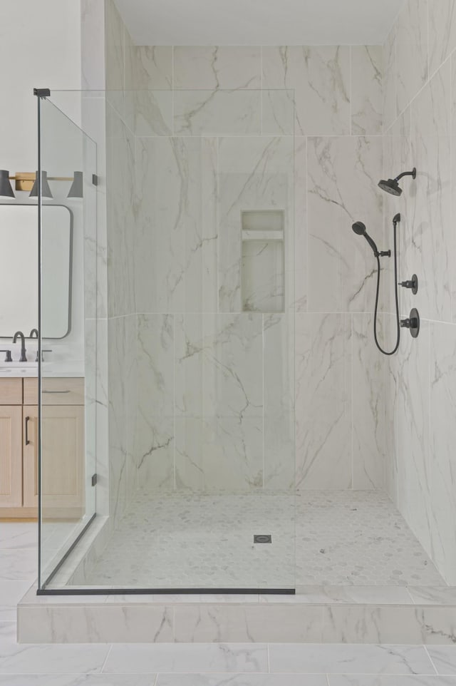 bathroom featuring a marble finish shower and vanity