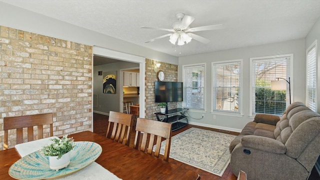 dining space featuring a textured ceiling, a fireplace, a ceiling fan, and wood finished floors