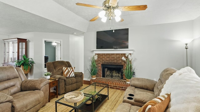 living area with a textured ceiling, ceiling fan, a brick fireplace, and wood finished floors