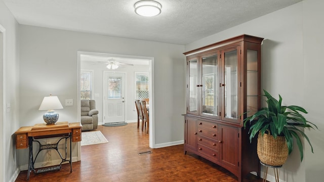 interior space with visible vents, dark wood finished floors, a textured ceiling, and baseboards