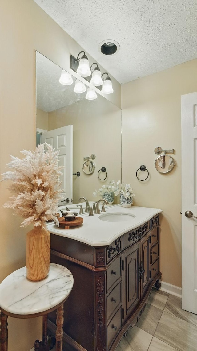 bathroom featuring a textured ceiling, vanity, and baseboards