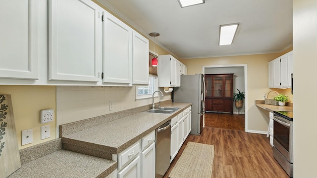 kitchen with stainless steel appliances, a sink, white cabinetry, light countertops, and dark wood finished floors