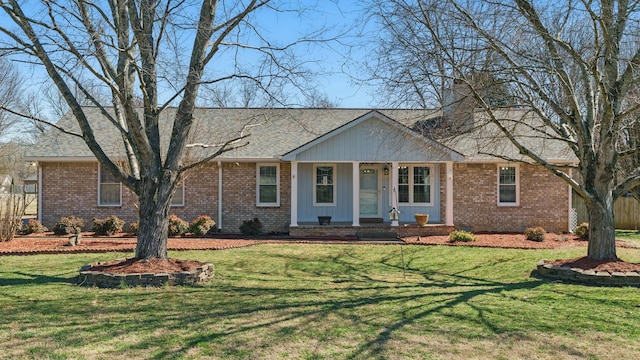 single story home featuring a front lawn, a chimney, and brick siding