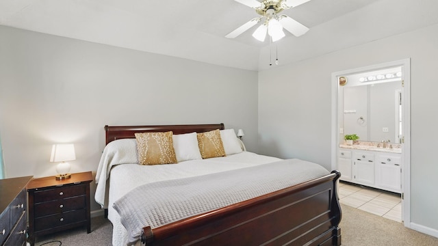 bedroom featuring a ceiling fan, ensuite bathroom, a sink, and light colored carpet