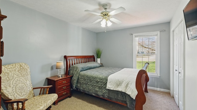 carpeted bedroom with a ceiling fan, a closet, and baseboards