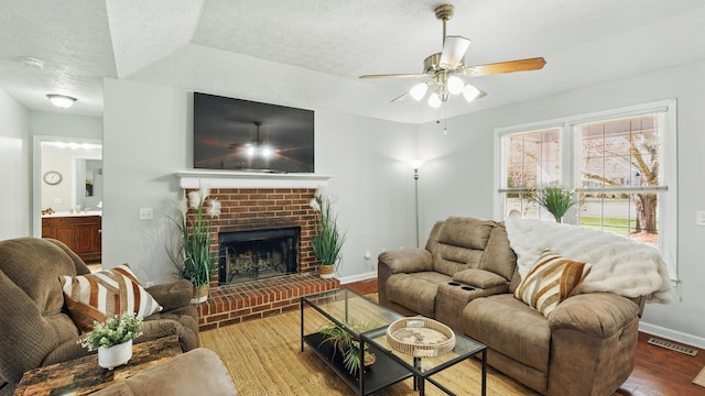 living room featuring a textured ceiling, a fireplace, wood finished floors, visible vents, and baseboards