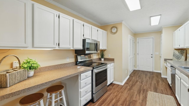 kitchen featuring light countertops, appliances with stainless steel finishes, wood finished floors, and white cabinetry