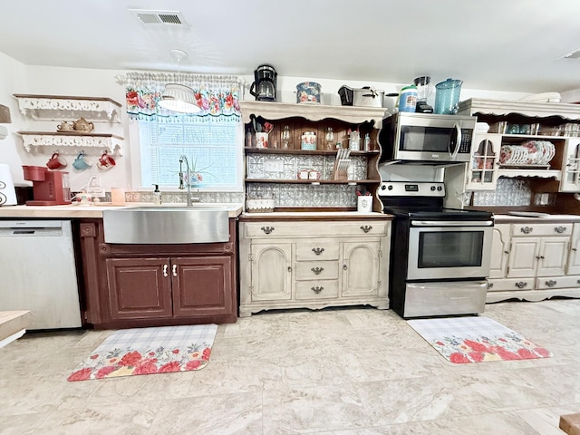 kitchen featuring visible vents, appliances with stainless steel finishes, open shelves, and a sink