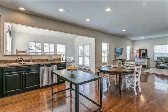 kitchen featuring open floor plan, wood finished floors, stainless steel dishwasher, a sink, and recessed lighting