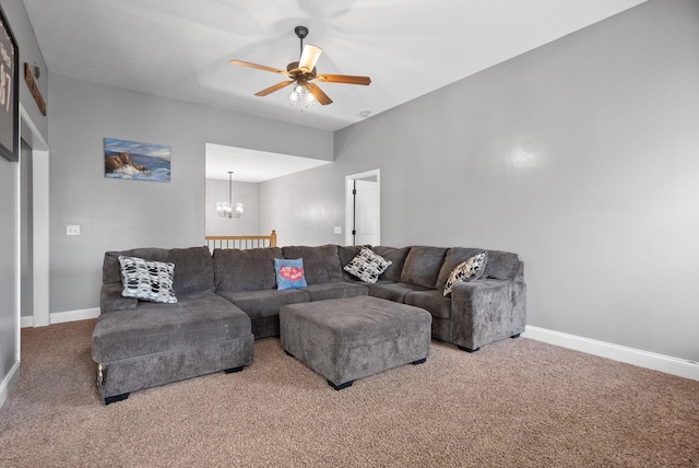 carpeted living area with ceiling fan with notable chandelier and baseboards