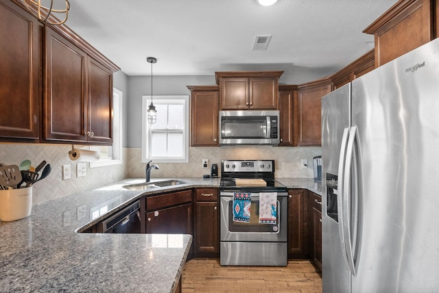 kitchen with visible vents, light wood-style flooring, appliances with stainless steel finishes, dark stone countertops, and a sink