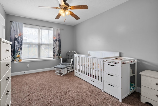 carpeted bedroom featuring a nursery area, ceiling fan, a textured ceiling, and baseboards