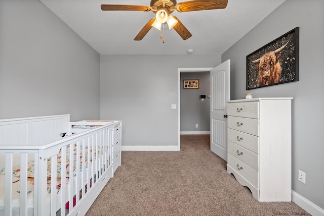 bedroom featuring ceiling fan, carpet floors, a crib, and baseboards