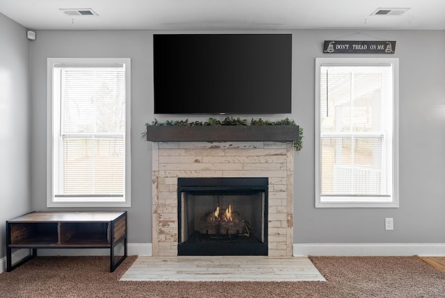 room details featuring carpet, a warm lit fireplace, visible vents, and baseboards