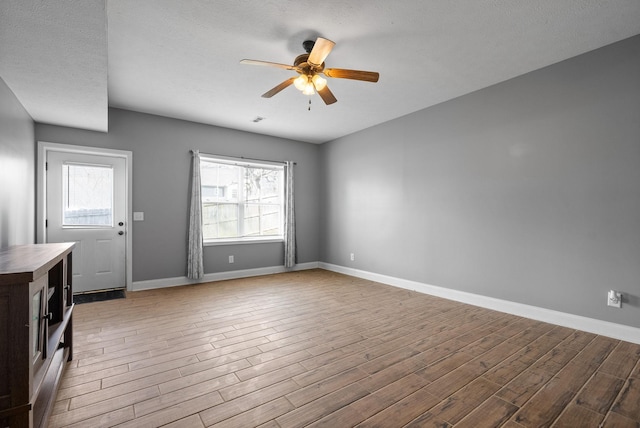 interior space with baseboards, wood finished floors, and a healthy amount of sunlight