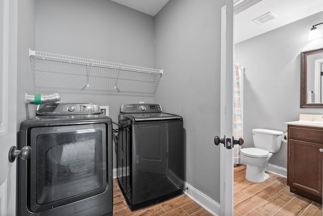 laundry area with laundry area, wood finish floors, visible vents, baseboards, and washing machine and clothes dryer