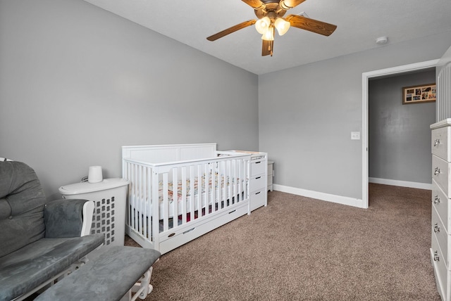 carpeted bedroom featuring ceiling fan, a crib, and baseboards