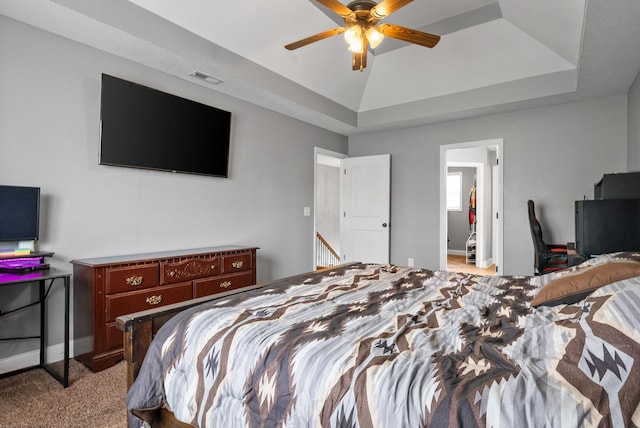 bedroom with light colored carpet, a tray ceiling, visible vents, and baseboards