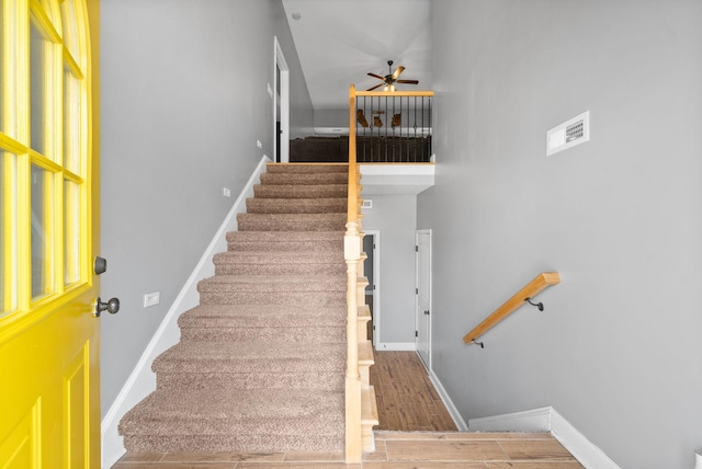 stairway with a ceiling fan, baseboards, and wood finished floors