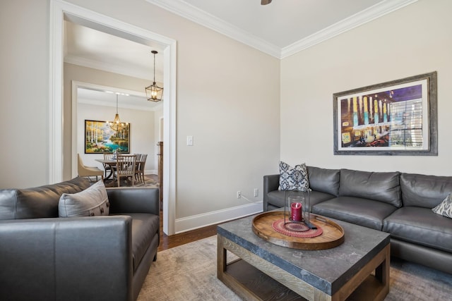 living room with an inviting chandelier, crown molding, baseboards, and wood finished floors