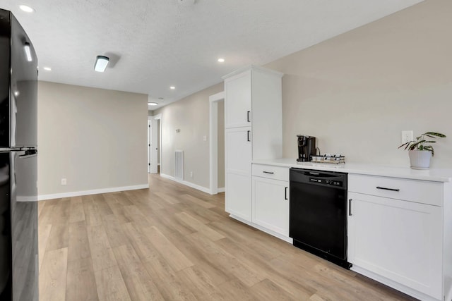 kitchen with light wood-style floors, black dishwasher, light countertops, and a textured ceiling