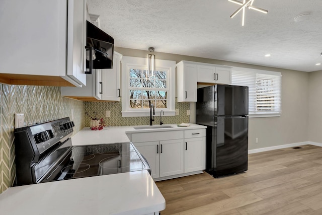 kitchen featuring electric stove, a sink, freestanding refrigerator, and a healthy amount of sunlight