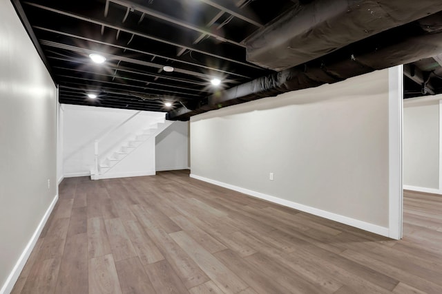 finished below grade area with stairway, wood finished floors, and baseboards