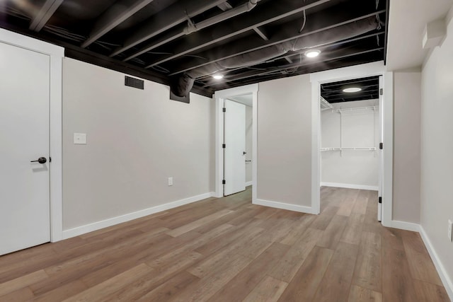 finished basement with light wood finished floors, visible vents, and baseboards