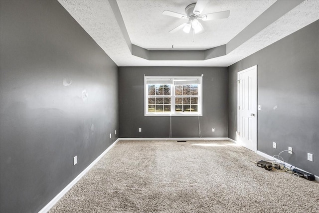 spare room featuring baseboards, a raised ceiling, a ceiling fan, a textured ceiling, and carpet floors