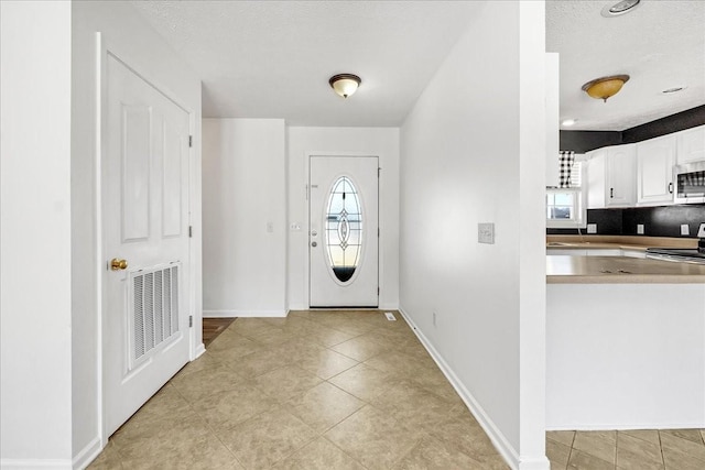 entryway featuring a textured ceiling, plenty of natural light, visible vents, and baseboards