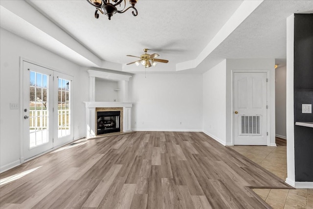 unfurnished living room with a textured ceiling, a raised ceiling, wood finished floors, and visible vents