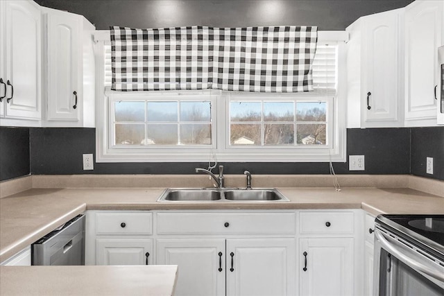 kitchen featuring light countertops, appliances with stainless steel finishes, a sink, and white cabinetry