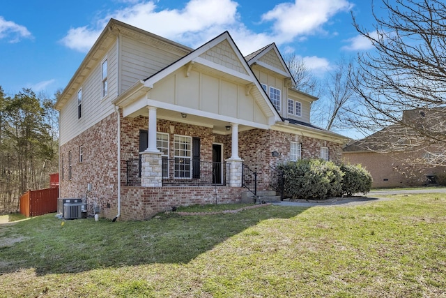 craftsman-style home with brick siding, cooling unit, board and batten siding, and a front yard