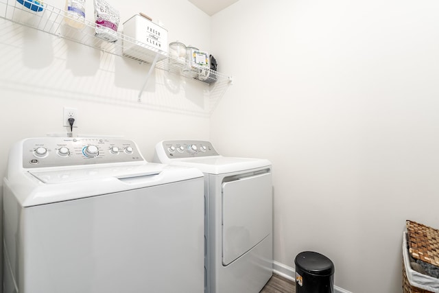 laundry area featuring laundry area, wood finished floors, washing machine and clothes dryer, and baseboards