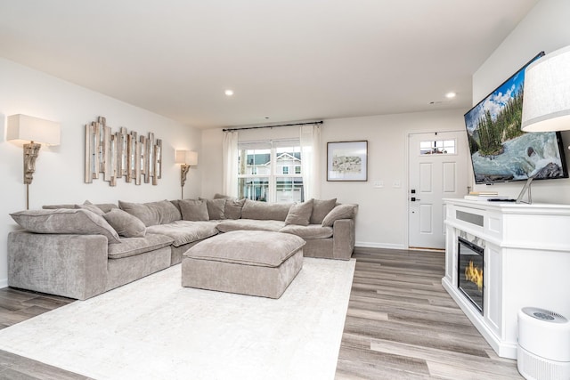 living room with light wood finished floors, recessed lighting, and a glass covered fireplace