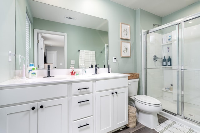 full bath featuring toilet, a sink, visible vents, double vanity, and a stall shower