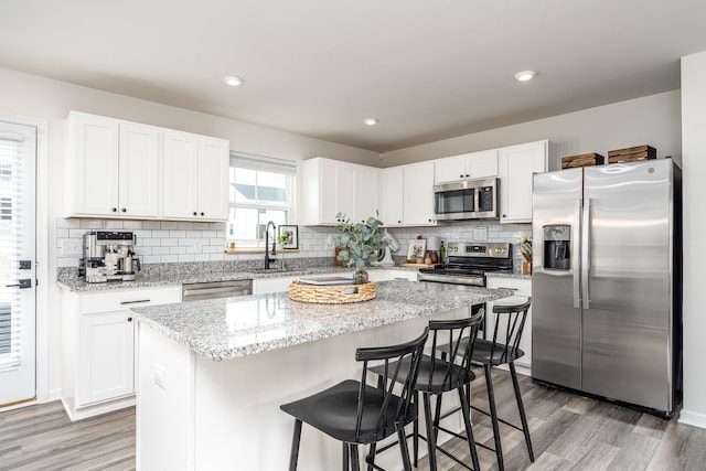 kitchen with light wood-style flooring, appliances with stainless steel finishes, and white cabinets