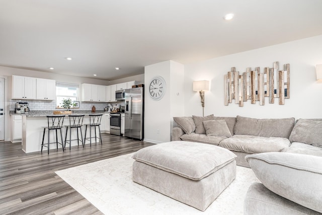 living room with dark wood-type flooring, recessed lighting, and baseboards