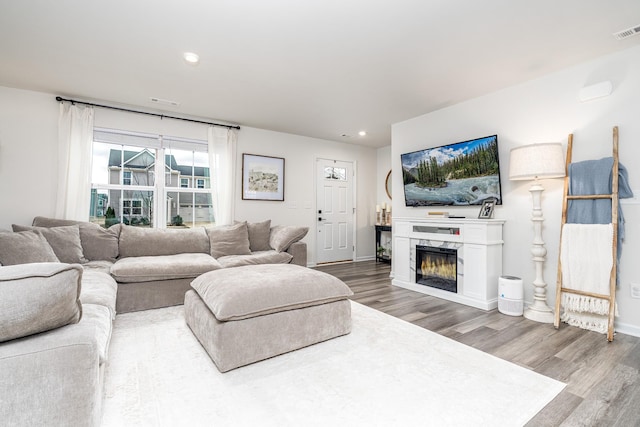 living area featuring visible vents, baseboards, a high end fireplace, wood finished floors, and recessed lighting