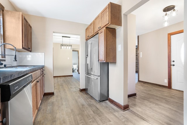kitchen featuring light wood-style floors, a sink, stainless steel appliances, and backsplash