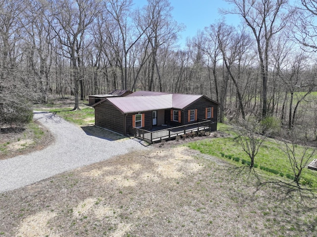 view of front of home featuring driveway, metal roof, and a view of trees