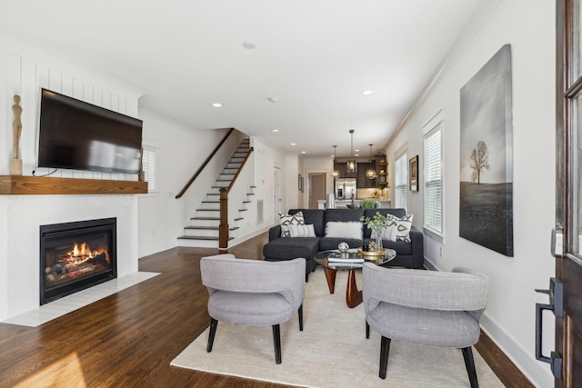 living area featuring baseboards, wood finished floors, stairs, a fireplace, and recessed lighting