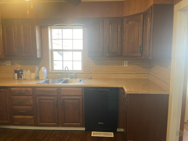 kitchen with dishwasher, light countertops, backsplash, and a sink