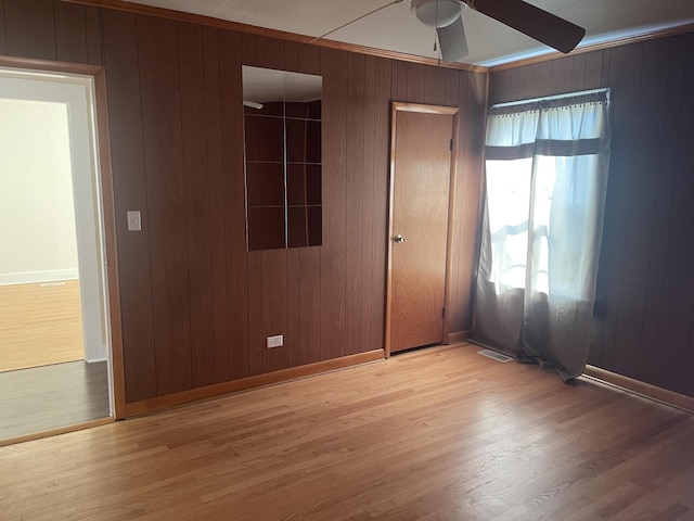 unfurnished bedroom featuring ornamental molding, ceiling fan, baseboards, and wood finished floors