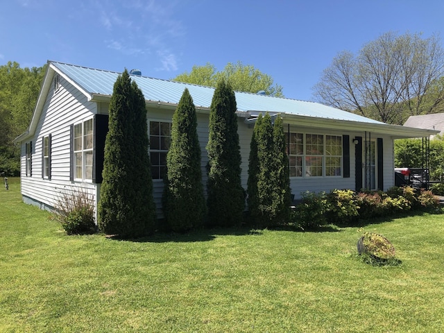 view of side of home with a yard and metal roof