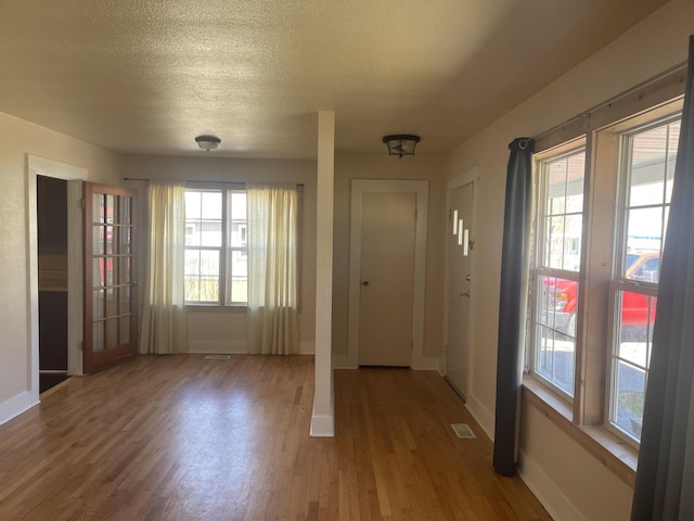 foyer with a wealth of natural light, visible vents, and wood finished floors